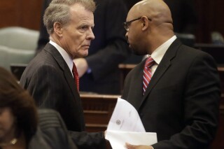 FILE -Illinois Speaker of the House Michael Madigan, D-Chicago, left, speaks with Illinois Rep. Thaddeus Jones, D-Calumet, right, while on the House floor after adjoining veto session, Thursday, Nov. 7, 2013 in Springfield Ill. Officials in a suburban Chicago community have issued municipal citations to a Hank Sanders, a local news reporter for what they say are persistent contacts with city officials for comment on treacherous fall flooding. Sanders continued to call and email city employees, drawing complaints including from Mayor Thaddeus Jones, who is also a Democratic state representative. (AP Photo/Seth Perlman, File)