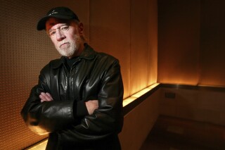 FILE - Actor and comedian George Carlin poses in a New York hotel March 19, 2004. Carlin's estate has filed a lawsuit against the media company behind a fake hourlong comedy special that purportedly uses artificial intelligence to recreate the late standup comic’s style and material. The lawsuit filed in federal court in Los Angeles on Thursday, Jan. 25, 2024, asks that a judge order the podcast outlet, Dudesy, to immediately take down the audio special, “George Carlin: I'm Glad I'm Dead, in which a synthesis of Carlin, who died in 2008, delivers commentary on current events. (AP Photo/Gregory Bull, File)