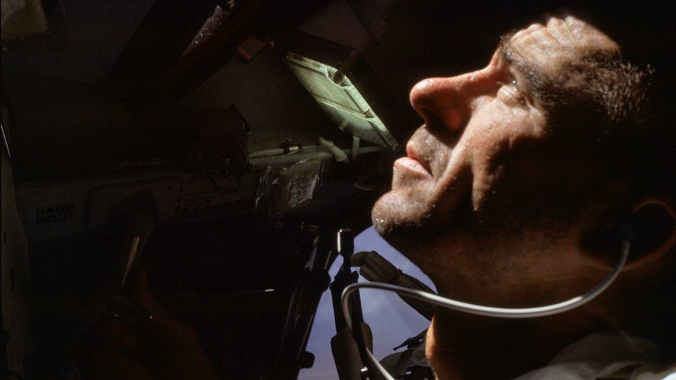 Walter Cunningham looks out a window from a spaceship