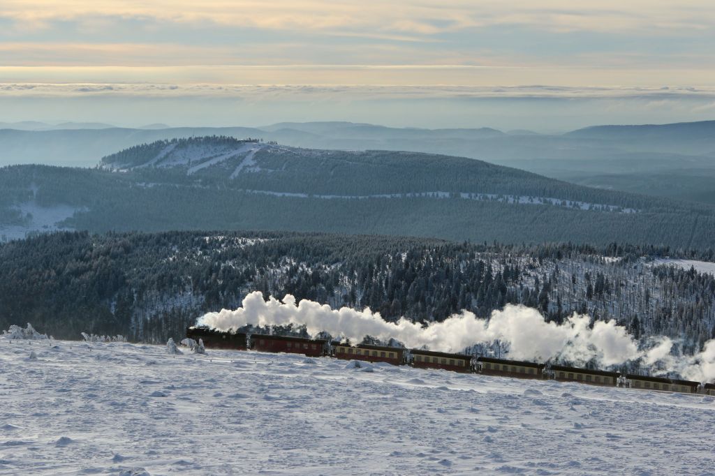 A steam train of the Harzer Schmalspurbahn narrow-gauge railway makes its way through the snowy landscape to reach the summit of the Brocken mountain in Schierke in the Harz region