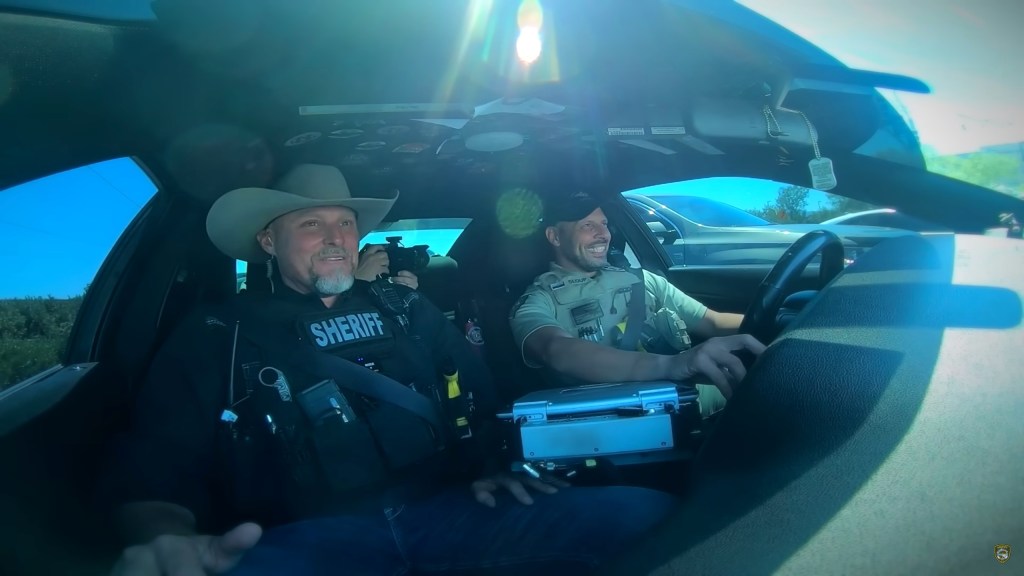 Sheriff Mark Lamb with Chris Sloup in the passenger seat of the deputy's cruiser.