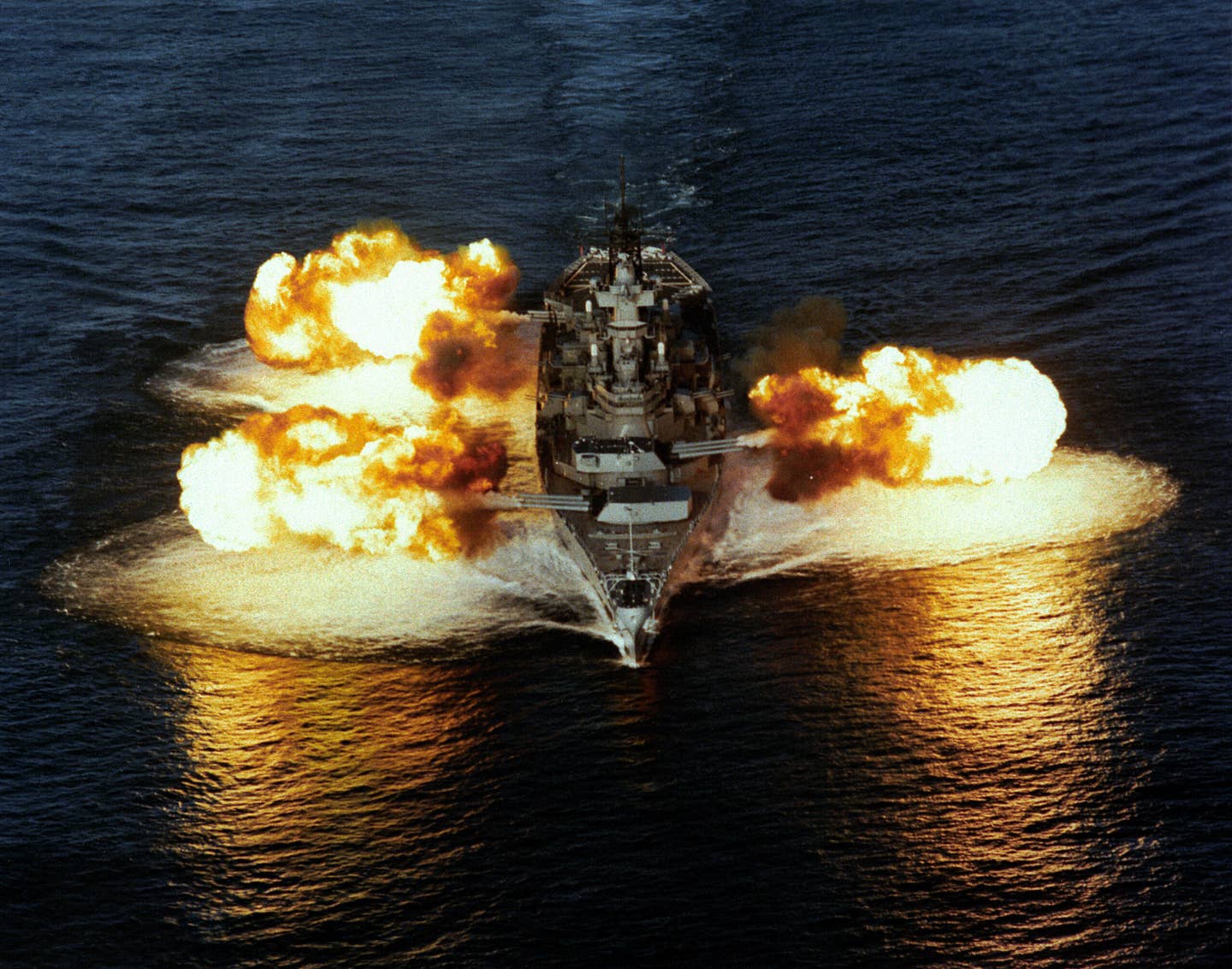 <em>Iowa</em> class USS New Jersey firing its nine 16-inch guns simultaneously during a demonstration in 1984. <em>USN</em>